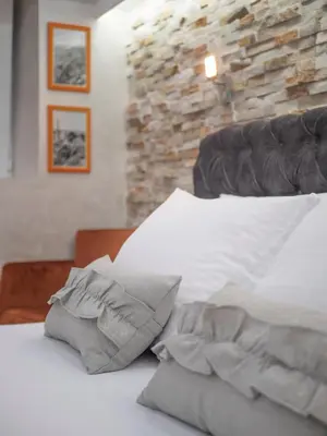 a bedroom with a white bed with a stone wall at Luxury Boutique Studio in Budva