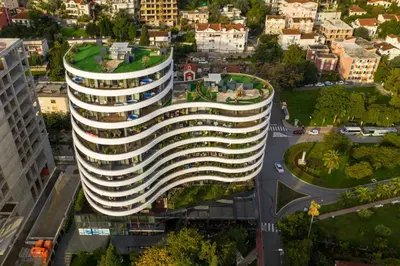 an office building with a curved facade in a city at Apartments Garden Azure Budva in Budva
