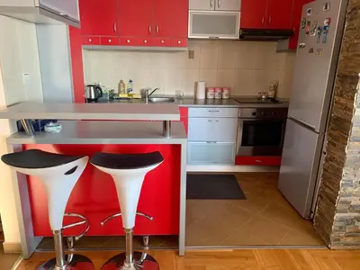 a kitchen with red cabinets and a counter with stools at Blue Sky Apartment in Petrovac na Moru