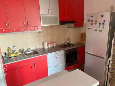 a kitchen with red cabinets and a white refrigerator at Blue Sky Apartment in Petrovac na Moru