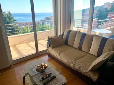a living room with a couch and a large window at Blue Sky Apartment in Petrovac na Moru
