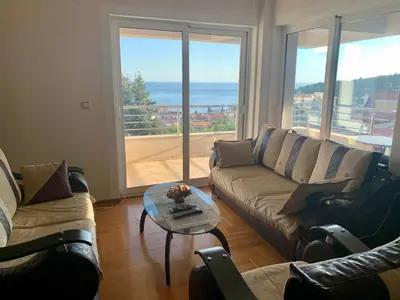 a living room with a couch and a table with a view at Blue Sky Apartment in Petrovac na Moru