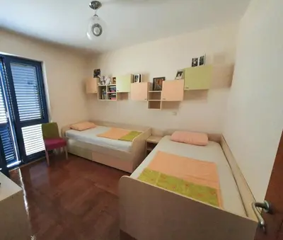 a room with two beds and a desk and a window at Apartman Azzuro in Pržno