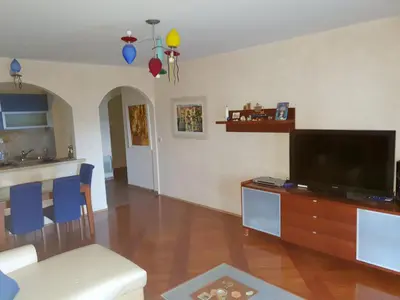 a living room with a flat screen tv on a wooden table at Apartman Azzuro in Pržno