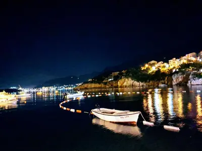 a boat is docked in the water at night at Apartman Azzuro in Pržno