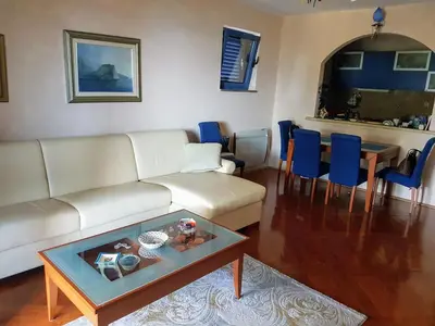 a living room with a white couch and a table at Apartman Azzuro in Pržno
