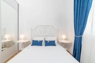 a bedroom with a white bed with blue curtains at Ana`s apartment Budva MNE in Budva