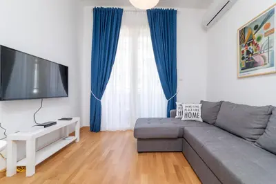 a living room with a gray couch and a flat screen tv at Ana`s apartment Budva MNE in Budva