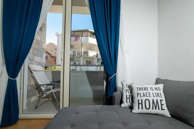 a room with a bed and a window with blue curtains at Ana`s apartment Budva MNE in Budva