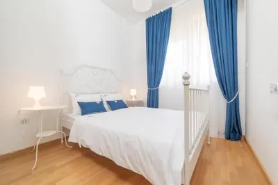 a bedroom with a white bed and blue curtains at Ana`s apartment Budva MNE in Budva