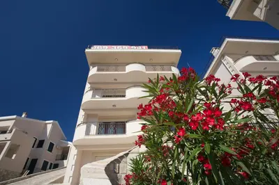 a white building with red flowers in front of it at St.George Apartments in Petrovac na Moru