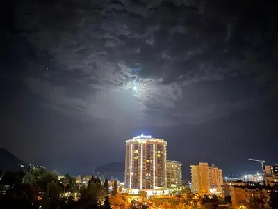 a view of a city at night with the moon at Lux Panorama in Budva