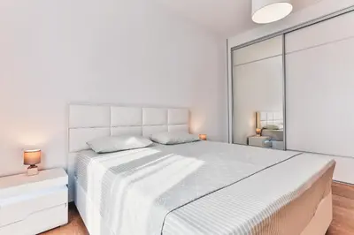 a white bedroom with a large bed and a window at Lux Panorama in Budva