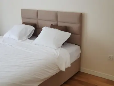 a bed with white sheets and pillows in a room at Apartman VIVO city central in Podgorica