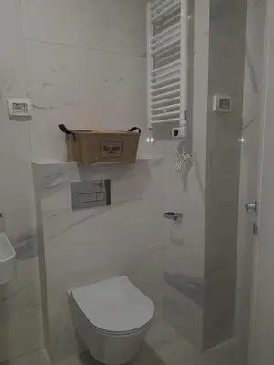 a white bathroom with a toilet and a sink at Apartman VIVO city central in Podgorica