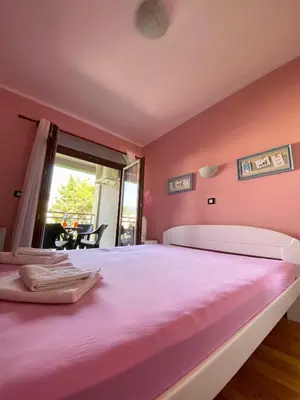 a pink bedroom with a large bed and a window at Apartment Center Adria in Bar