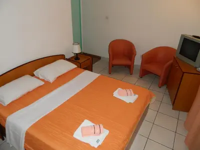 a bedroom with a bed and two chairs and a television at Mena apartmani in Budva