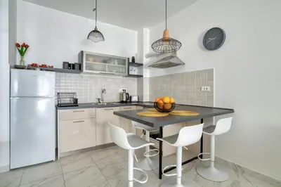 a kitchen with a table with chairs and a refrigerator at Ada apartman in Budva