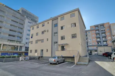 a building with a car parked in a parking lot at Ada apartman in Budva