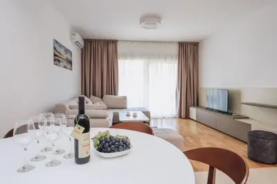a living room with a table with a bottle of wine and wine glasses at Status-M Аpartments 173 in Becici