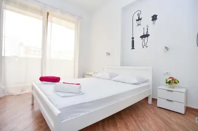a white bedroom with a large white bed and a window at Victoria Center Apartments in Budva