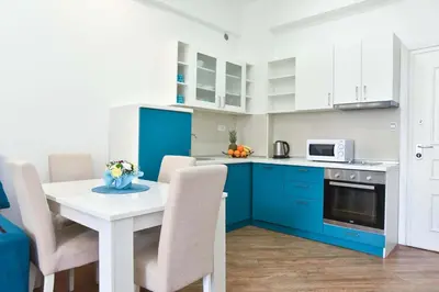 a kitchen with blue cabinets and a table with chairs at Victoria Center Apartments in Budva
