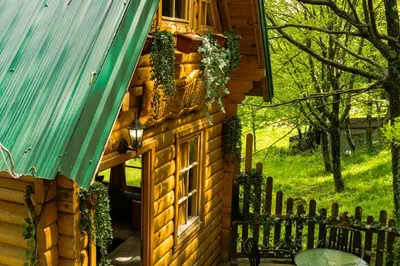 a log cabin with a green roof and a fence at Brvnara Fairy Tale in Cetinje