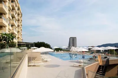 a swimming pool with chairs and umbrellas next to a building at Status-M Apartments 179 in Becici