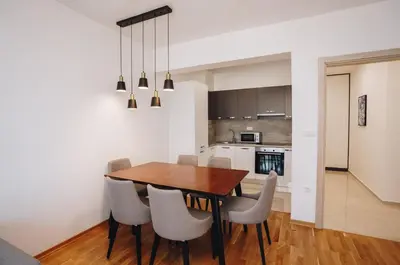 a kitchen and dining room with a wooden table and chairs at Status-M Apartments 205 in Becici