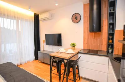 a small kitchen with a table and a tv at Design Apartment near Gorica Park in Podgorica