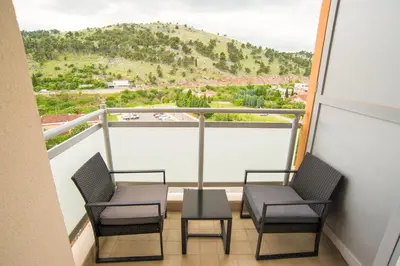 two chairs and a table on a balcony with a mountain at Design Apartment near Gorica Park in Podgorica