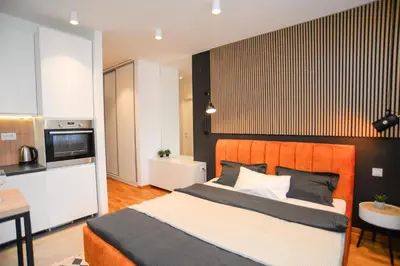 a bedroom with a large bed and a kitchen at Design Apartment near Gorica Park in Podgorica
