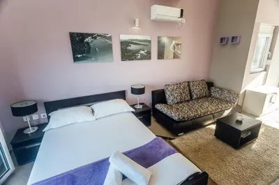 a bedroom with a bed and a couch and a chair at Beachfront Apartments Tivat in Tivat