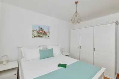 a white bedroom with a bed and a white cabinet at Villa Forest & Blue in Kotor