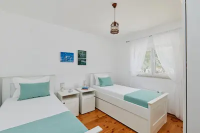 a white bedroom with two beds and a window at Villa Forest & Blue in Kotor