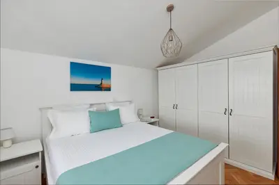 a white bedroom with a bed and white cabinets at Villa Forest & Blue in Kotor