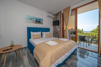a bedroom with a bed and a balcony at Green Pino Seaview Studios in Bar