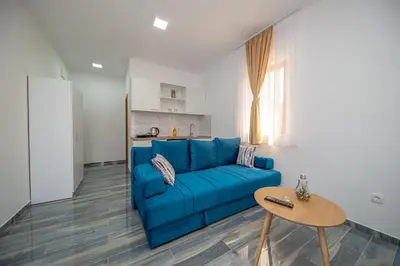 a living room with a blue couch and a table at Green Pino Seaview Studios in Bar