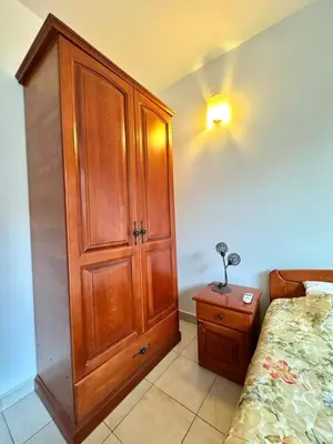 a bedroom with a wooden cabinet next to a bed at The Four Fish in Petrovac na Moru