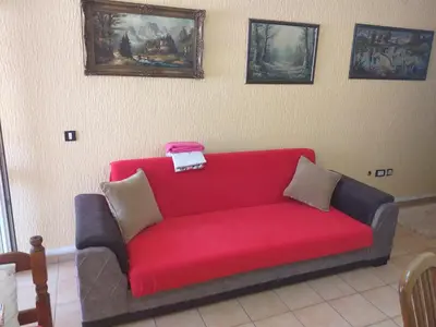 a red couch in a room with paintings on the wall at Apartman Sutomore in Sutomore