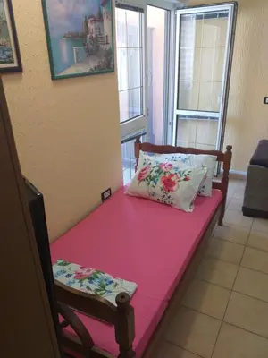 a bed with a pink sheet and two pillows on it at Apartman Sutomore in Sutomore