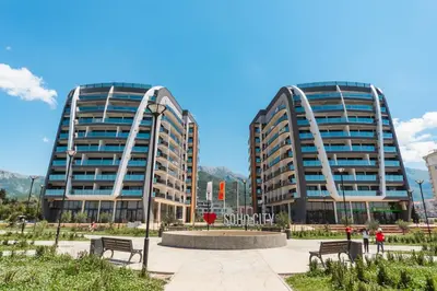 two tall buildings in a park with benches in front at Soho City A403 in Bar