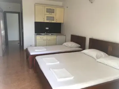 two twin beds in a room with a kitchen at Apartments ND in Bar
