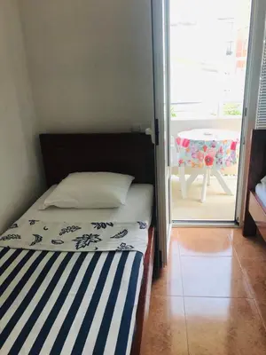 a bedroom with a bed and a balcony with a table at Apartments ND in Bar