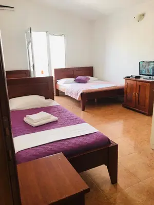 a room with two beds and a wooden table at Apartments ND in Bar