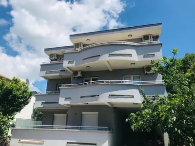 a tall white building with trees in front of it at Apartments ND in Bar