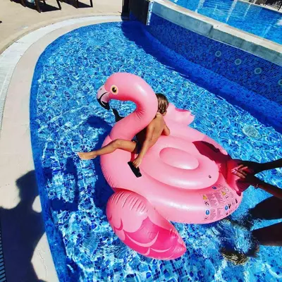 a man riding a pink flamingo in a pool at Blue Horizon Lux Apartment with Pool in Sveti Stefan