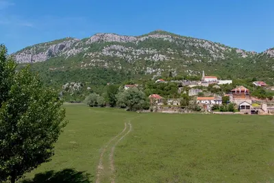 a green field with a mountain in the background at Pristan Apartments in Dodoši