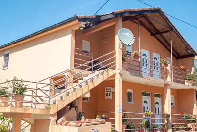 a building with a balcony and stairs on it at Pristan Apartments in Dodoši