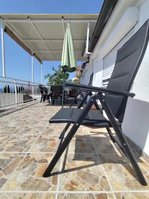 a chair and an umbrella on a patio at Apartman Kosta in Utjeha